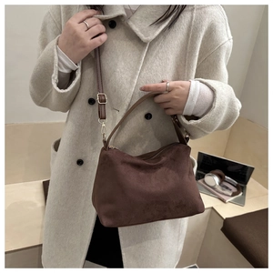 Detail of dark brown faux suede hobo bag with adjustable strap worn on wool coat