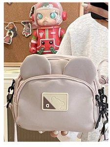 Close-up of a cute pink nylon crossbody bag with 3D bear ears and letter D patch