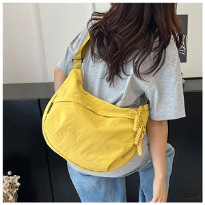 Modèle portant un grand sac croissant en nylon jaune vif avec une large bandoulière