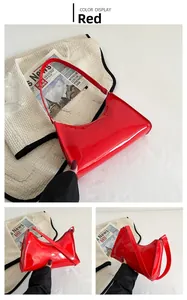 Détail du sac baguette en cuir verni rouge montrant la forme en demi-lune et la texture
