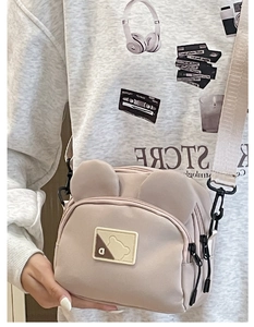 Detail of cute bear ear design and textured canvas material on beige crossbody bag