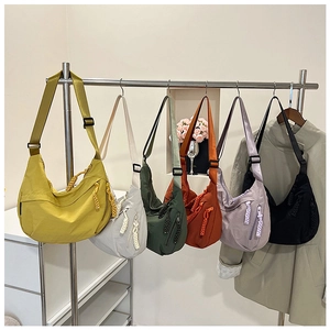 Sélection de sacs bandoulière croissants en nylon colorés suspendus sur un support de vente