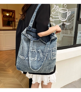 Detail shot of distressed LOVE lettering with frayed edges on a vintage blue denim tote bag
