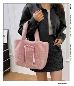 Pink plush tote bag with ribbon bow detail styled on a model in a leather jacket