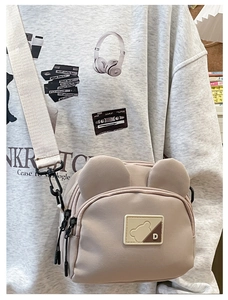 Detail of cute bear crossbody bag with wide shoulder strap and character logo patch