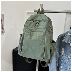 Detail view of forest green water-resistant nylon backpack hanging on a metal rack