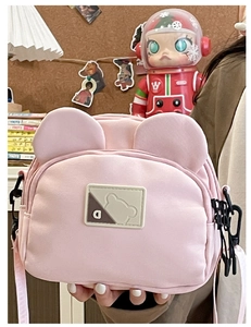 Detail of pink canvas crossbody bag with cute bear ears and textured plastic hooks