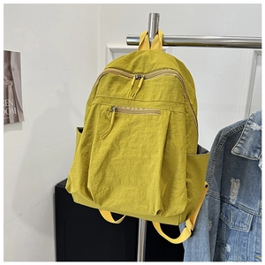 Detail showing bright yellow waterproof nylon backpack with multi-zipper compartments