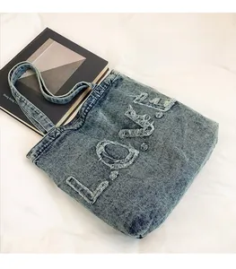 Close-up of distressed denim tote bag featuring a unique ripped LOVE letter pattern