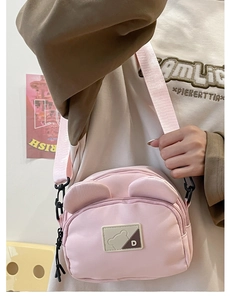 Detail of pink canvas crossbody bag featuring cute bear ear accents and adjustable strap