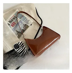 Comparaison de taille d'un sac baguette en cuir verni marron avec une coque de téléphone