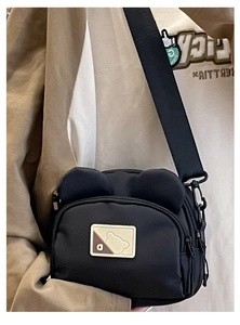Detail view of the black bear-ear canvas crossbody bag showing the strap and side pocket