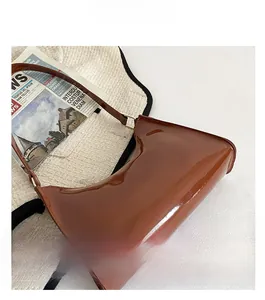 Détail d'un sac baguette marron brillant sur un fond en tricot élégant