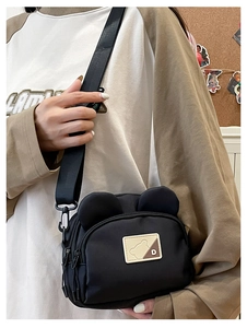 Detail of cute bear-eared black crossbody bag with adjustable nylon strap and logo patch