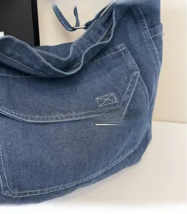 Détail du sac cabas en denim bleu foncé avec surpiqûres blanches et poche plaquée