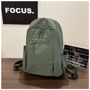 Close-up of water-resistant gray-green nylon backpack on a minimalist wooden desk