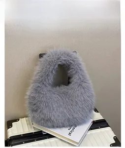 Détail d'un sac à main gris en fausse fourrure posé sur une valise et des livres