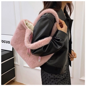 Detail view of large pink plush tote bag with drawstring on a stylish female model