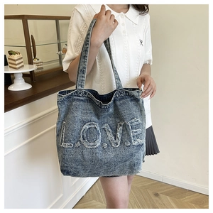 Detail of vintage blue denim tote bag featuring frayed 3D LOVE letter embroidery