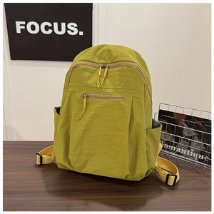 Close-up of mustard green water-resistant nylon backpack with hidden zipper on wooden table