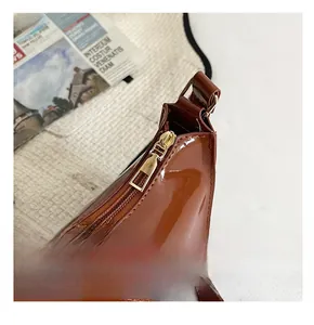 Gros plan détaillé de la fermeture éclair dorée sur le sac en cuir verni marron