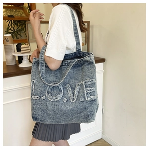 Detail of vintage washed denim tote bag featuring frayed LOVE patch on deep blue fabric