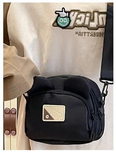 Detailed view of black nylon crossbody bag featuring cute bear ears and adjustable strap