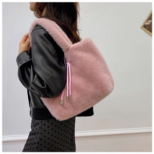 Detail of pink faux fur tote bag with drawstring tassels worn over a black leather jacket