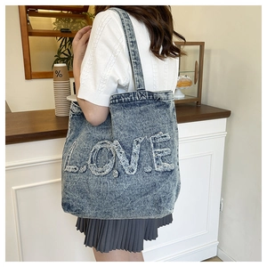 Detail of vintage washed denim tote bag featuring white LOVE lettering with frayed edges