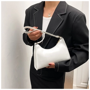 Sac sous le bras blanc minimaliste avec boucles dorées porté par un mannequin chic