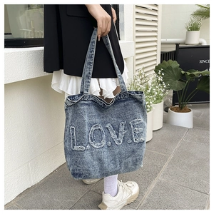 Detail of vintage washed denim tote bag featuring frayed L.O.V.E. letter patchwork embroidery