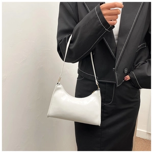 Détail du sac baguette en cuir verni blanc avec des accessoires en métal doré brillant