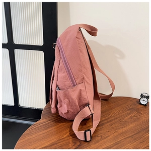 Side view of pink water-resistant nylon backpack with side pocket and canvas straps