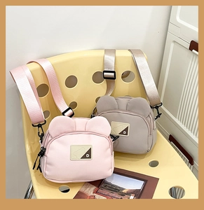 Detail showing the bear-shaped nylon crossbody bag with adjustable wide strap and D label