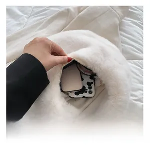 Interior view of white faux fur handbag showing storage space for phone and makeup