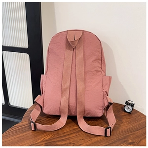 Rear view of a pink water-resistant nylon backpack with adjustable straps and side pockets