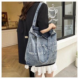 Close-up of vintage washed denim tote bag featuring distressed LOVE patch and frayed details