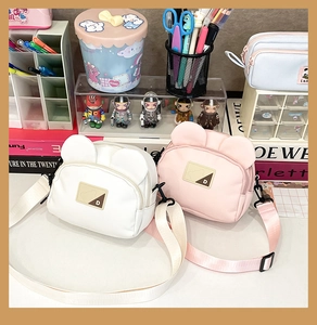 Detail view of cute cartoon bear ear canvas crossbody bags in white and pink color options