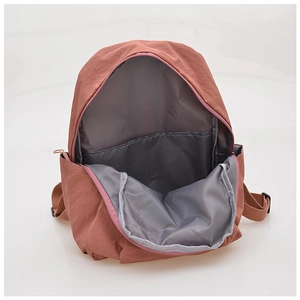 Detail view of the brick red nylon backpack interior featuring gray lining and pocket