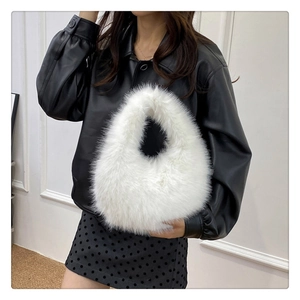 Détail d'un sac à main blanc en fausse fourrure montrant la texture douce et l'anse intégrée