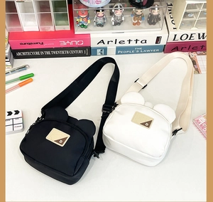Close-up of black and white bear-shaped canvas crossbody bags with adjustable straps
