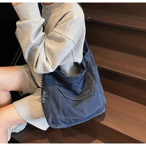 Détail du sac cabas en denim bleu avec surpiqûres blanches et bords usés style vintage