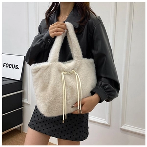 White plush tote bag with drawstring tassels shown styled with a black leather jacket