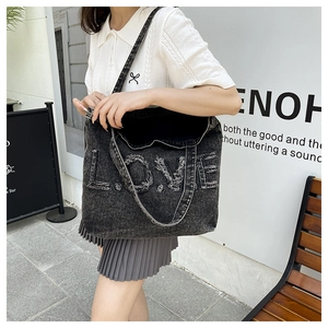 Close-up of black acid wash denim tote bag with LOVE patch and frayed edges