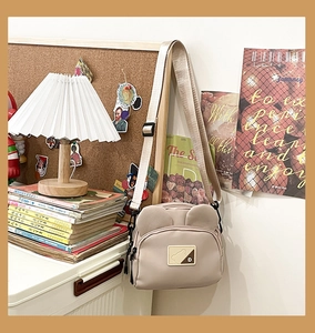 Detail view of a cute apricot mini crossbody bag with 3D bear ears and shoulder strap