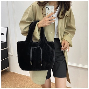 Fashionable black faux fur tote bag with drawstring detail shown on a female model