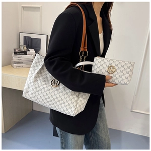 Detail of stylish monogram tote bag with matching pouch and golden metal logo charm