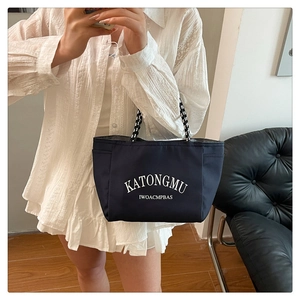 Detail of navy tote bag with white lettering and black and white checkered strap