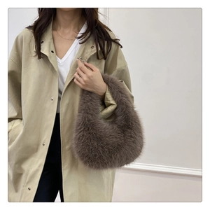 Sac à main chic en peluche marron foncé porté avec un trench-coat kaki pour l'automne