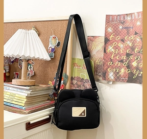 Detail of cute bear ears design on black canvas crossbody bag with adjustable strap
